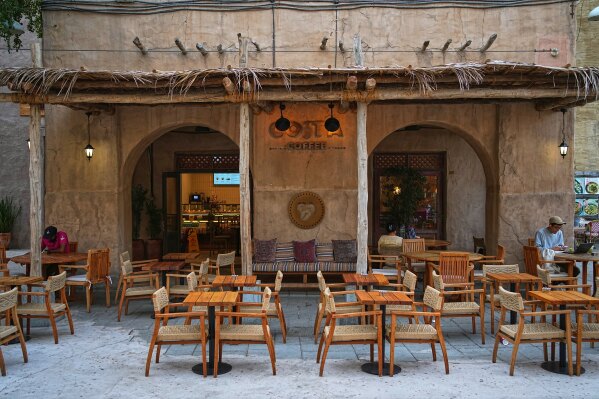 Few clients sit amid empty chairs in a cafe at the Al Seef market, next to the historic Al Fahidi neighborhood along Dubai Creek, one of the main tourist areas of Dubai, United Arab Emirates, Friday, March 13, 2026, as tourism slows amid regional tensions linked to the Iran war. (AP Photo/Fatima Shbair)