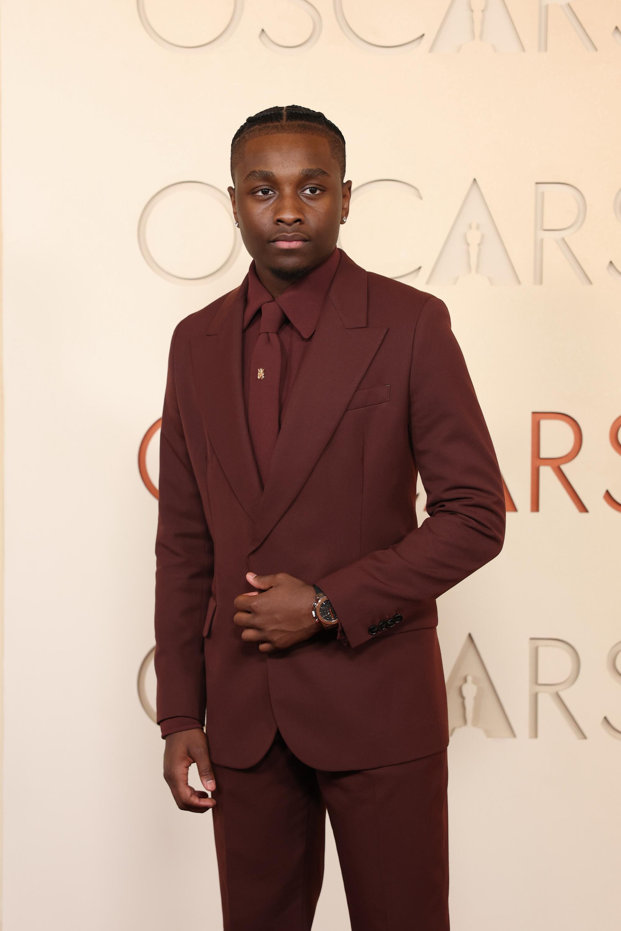 Miles Caton, in an all-brown suit, poses on the red carpet. 
