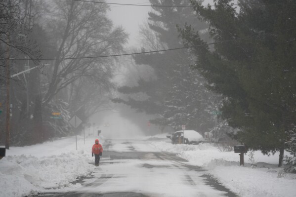 A person walks down a snowy street, Sunday, March 15, 2026, in St. Paul, Minn. (AP Photo/Abbie Parr)