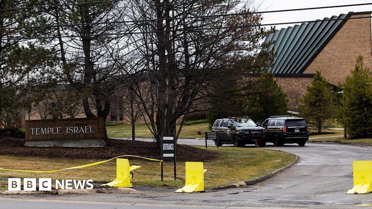 view of the Temple Israel sign out front of the synagogue, with police cars and yellow tape in view