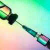 vaccination syringe and bottle on a colored background. close up, copy space