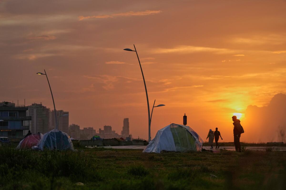 People walking past tents sheltering people displaced by Israeli airstrikes