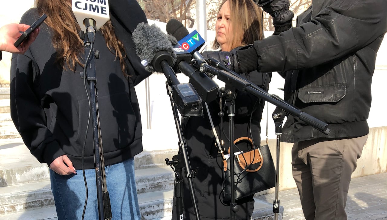 People in front of microphones. The head of the person speaking is not shown because of a court-ordered ban on their identity.