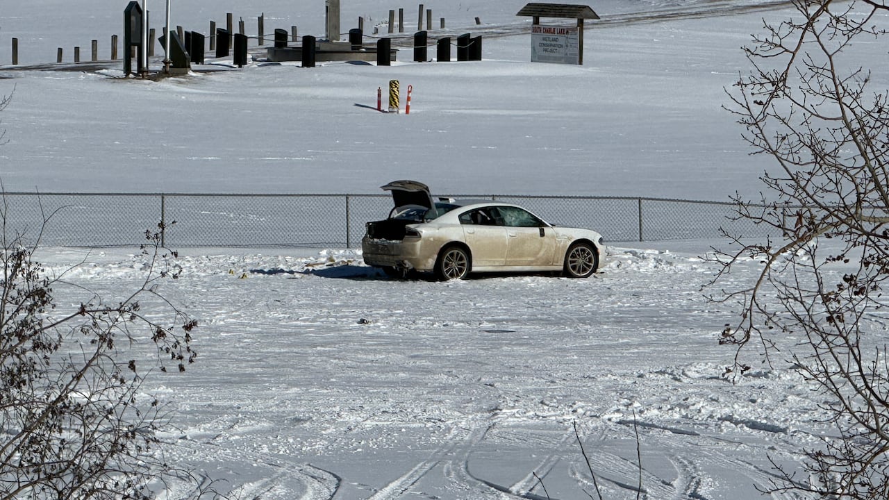 A car is seen near a snowy boat ramp.
