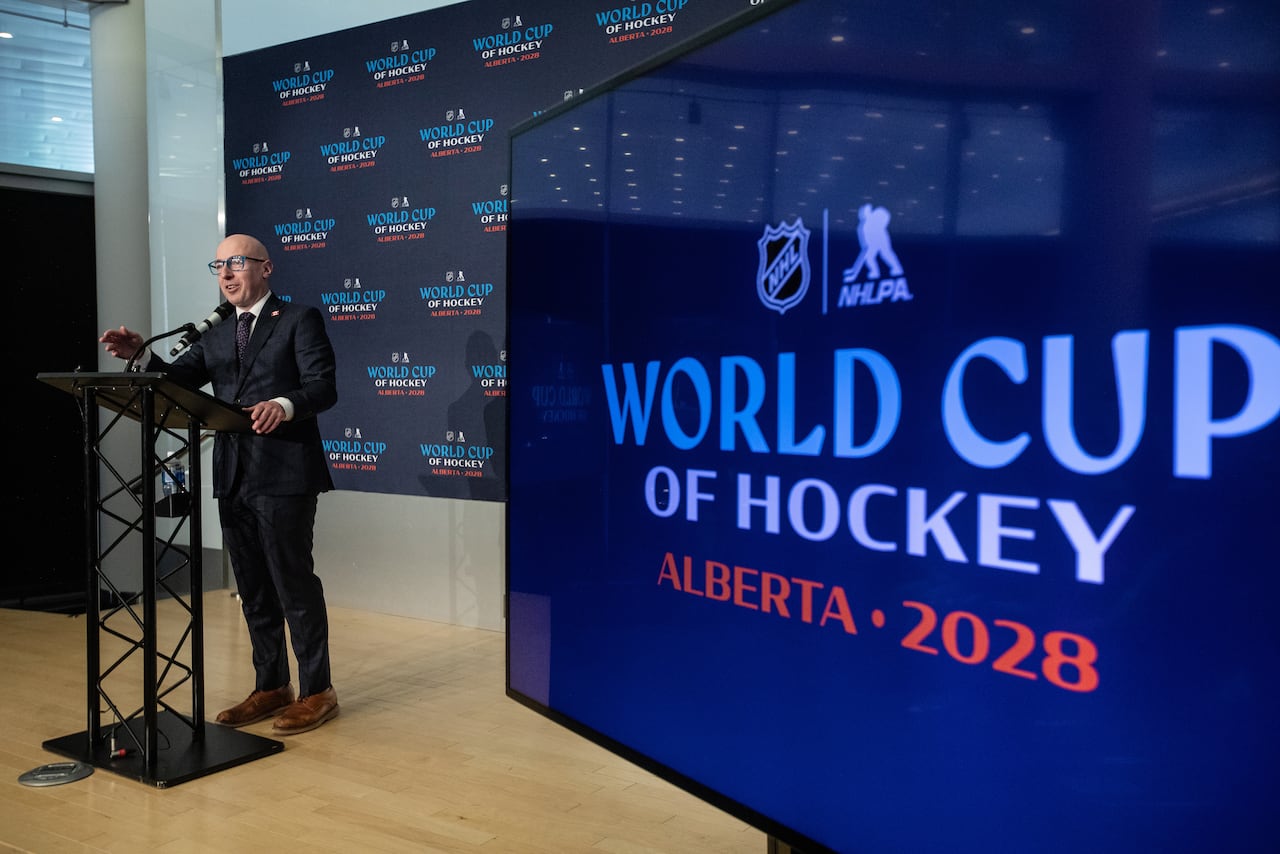 A man stands next to a screen at a podium.
