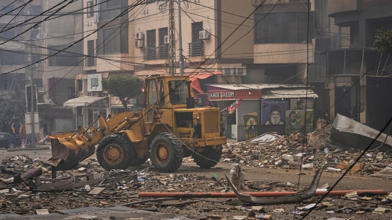 A bulldozer clears debris from the rubble of buildings destroyed...