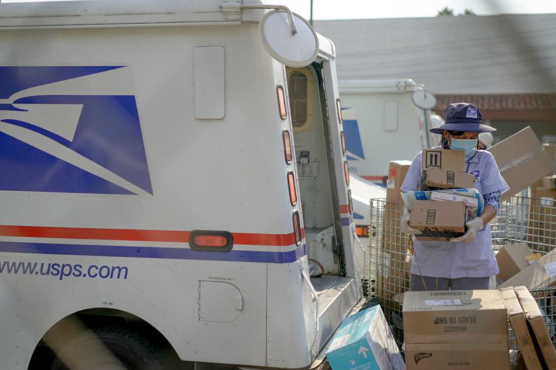 A U.S. Postal Service worker sorts packages behind a mail truck in Los Angeles in 2020.