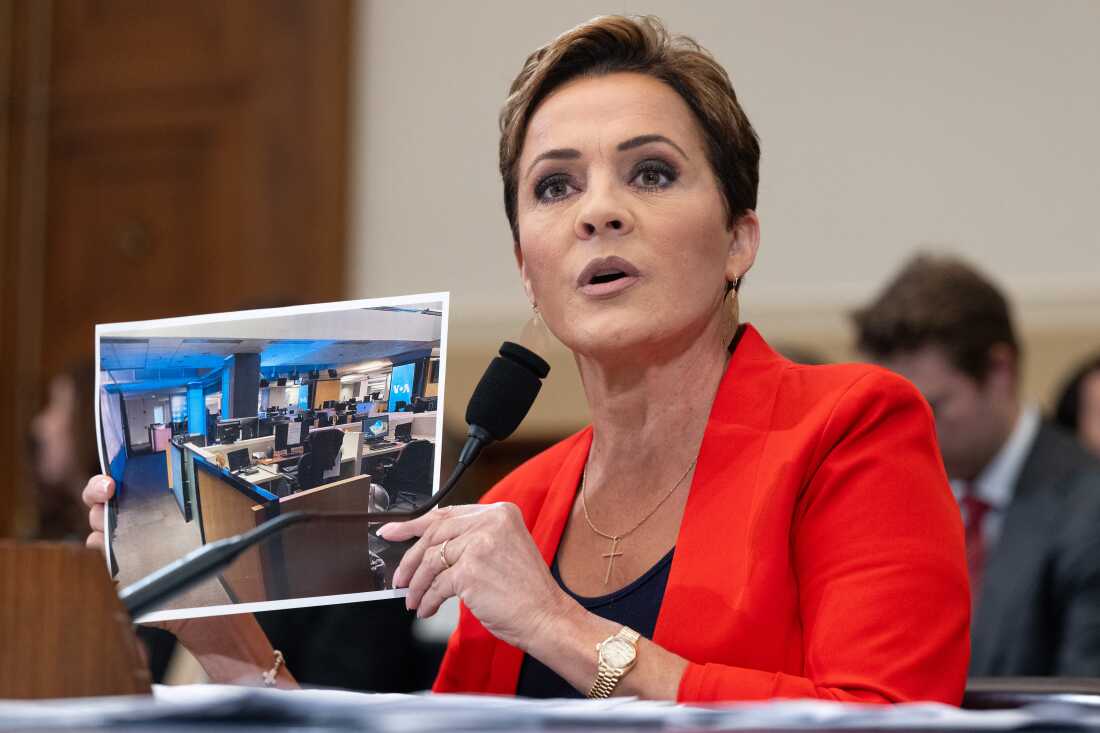 Kari Lake, who led Voice of America's parent agency for much of last year, holds up a photo of the international broadcaster's newsroom during a House Foreign Affairs Committee hearing on June 25, 2025.