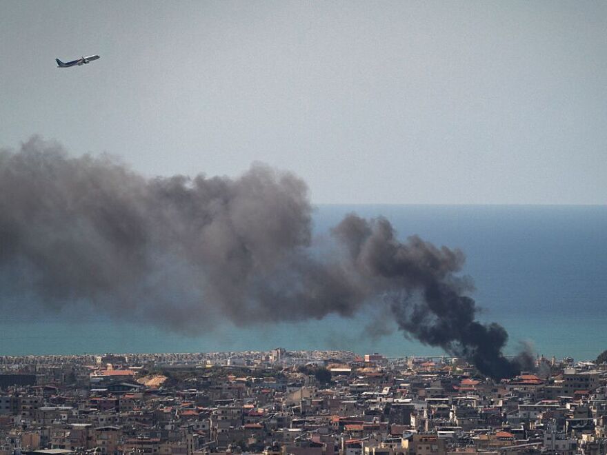 MEA commercial airplane is flying above the smoke after an IDF airstrike on March 17, 2026 in Beirut, Lebanon.