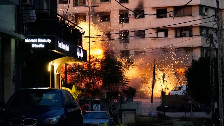 Explosions erupt from a building following an Israeli strike in...