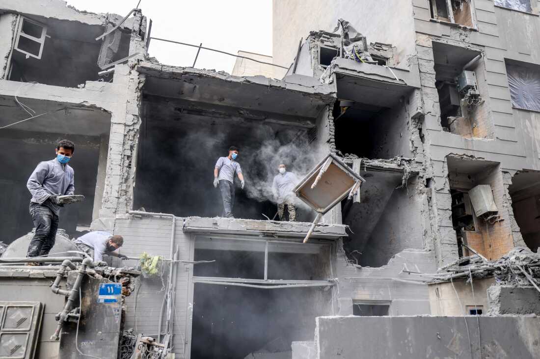 Iranians clear the debris from damaged homes following a military strike in the Iranian capital Tehran on March 15, 2026.