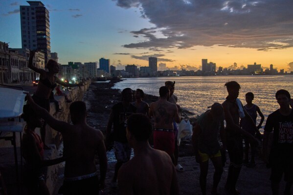 People watch the sunset from the Malecón during a blackout in Havana, Monday, March 16, 2026. (AP Photo/Ramon Espinosa)