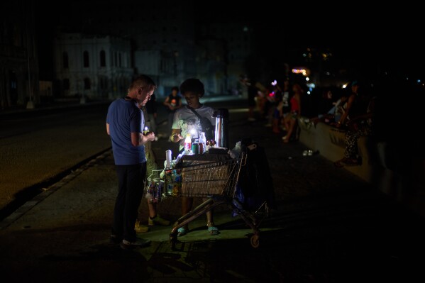 A street vendor tends to a customer on the Malecón during a blackout in Havana, Monday, March 16, 2026. (AP Photo/Ramon Espinosa)