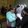 Two women look over their documents by a line snaking around the block outside the San Francisco Immigration Court in 2019.