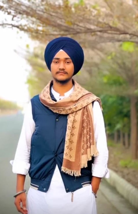 A man in a blue turban and white robes with blue jacket