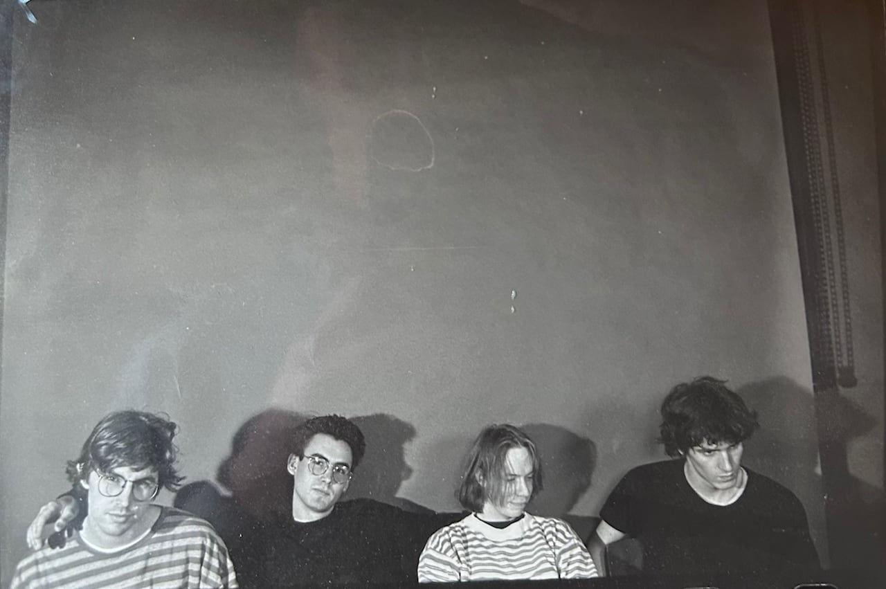 Four young men from a rock band are shown in a black-and-white photo.
