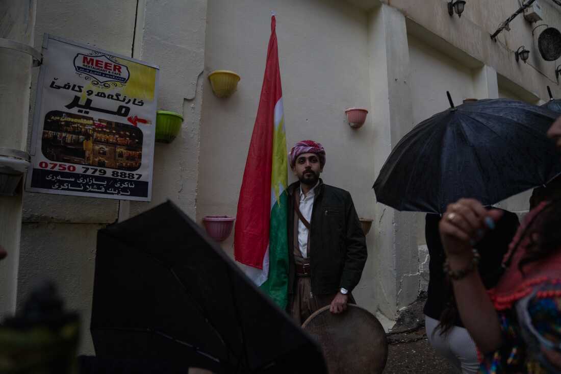 Ismail Mohammad, 28, holds a Kurdish flag and a drum as people pass by at the Nowruz festivities.