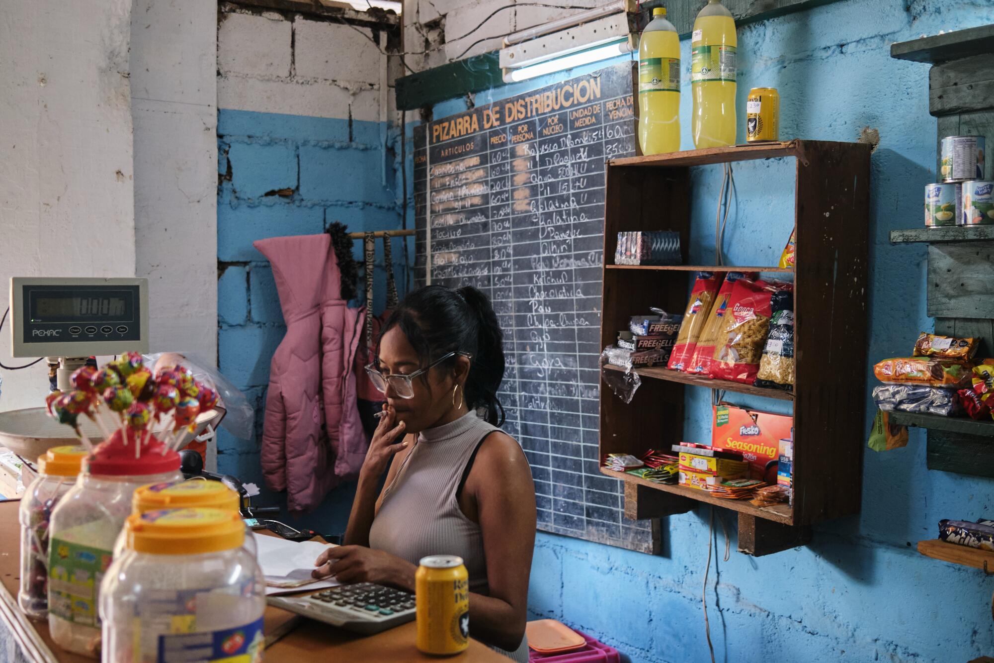 An employee of a grocery sells vegetables and other goods
