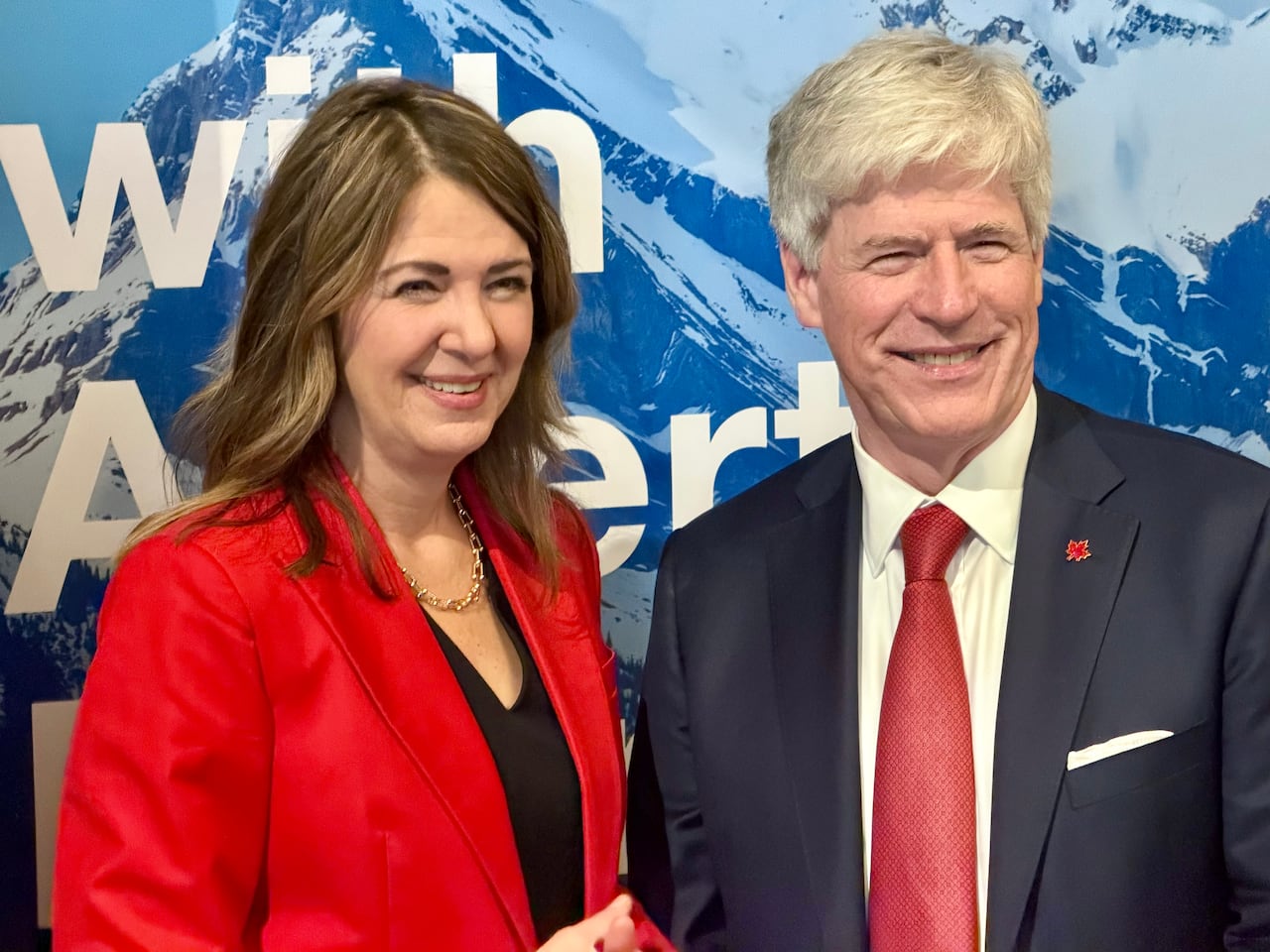 Two politicians smile as their photo is taken.