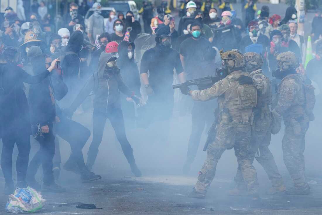 U.S. Customs and Border Protection agents standoff against demonstrators as tear gas fills the air outside the federal ICE building during a protest in Portland, Ore., on June 14, 2025.