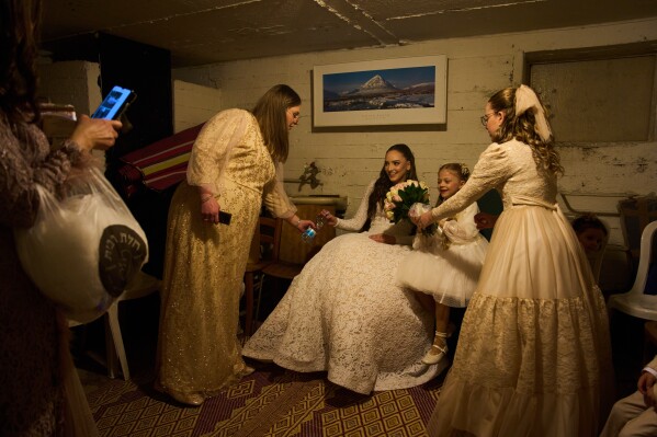 A bride and her family sit in a bomb shelter after an alert warning of missiles fired from Iran toward central Israel interrupted their wedding photo shoot in a nearby park in Ramat Gan, Israel, Thursday, March 19, 2026. (AP Photo/Oded Balilty)