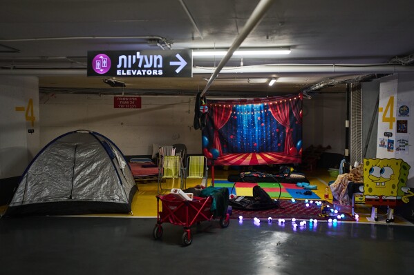 Tents, mattresses and children's toys are spread across an underground parking garage where people spend the night as a precaution against possible Iranian missile attacks in Tel Aviv, Israel, Thursday, March 12, 2026. (AP Photo/Oded Balilty)