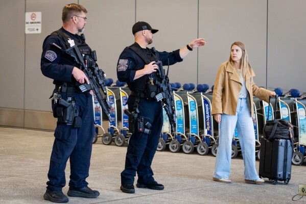A traveler speaks to police officers at Los Angeles International Airport on Monday, March 23, 2026, in Los Angeles. (AP Photo/Ethan Swope)