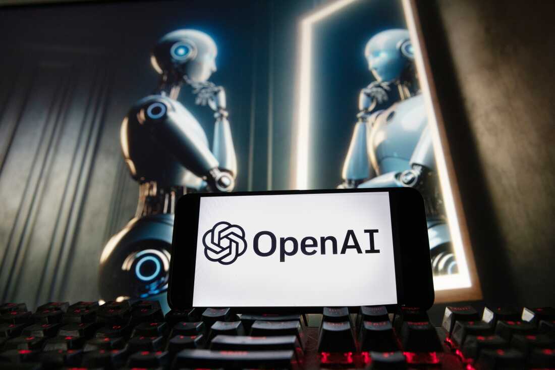 FILE - The OpenAI logo is displayed on a cellphone with an image on a computer monitor generated by ChatGPT's Dall-E text-to-image model, Dec. 8, 2023, in Boston.