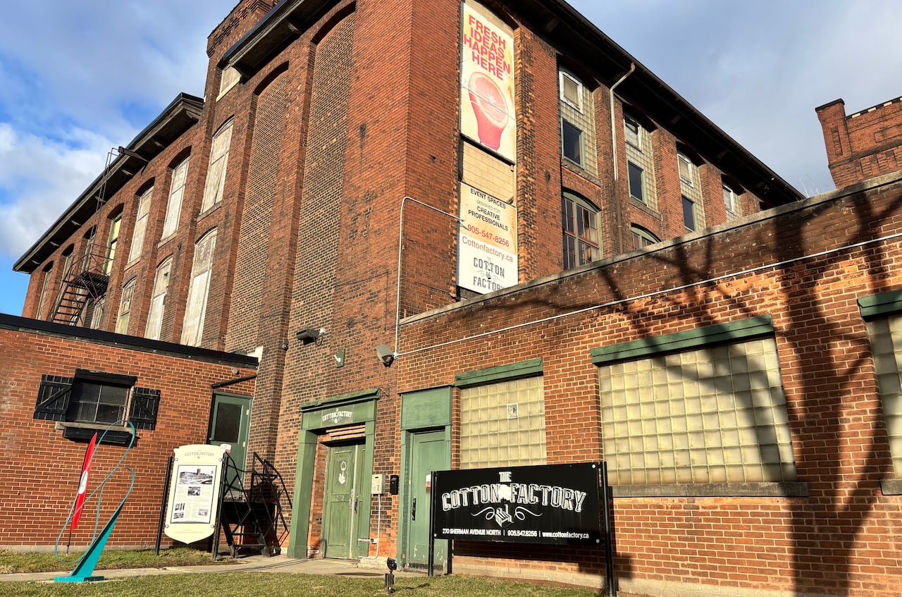 A photo of a retrofitted brick factory with a sign reading The Cotton Factory out front.