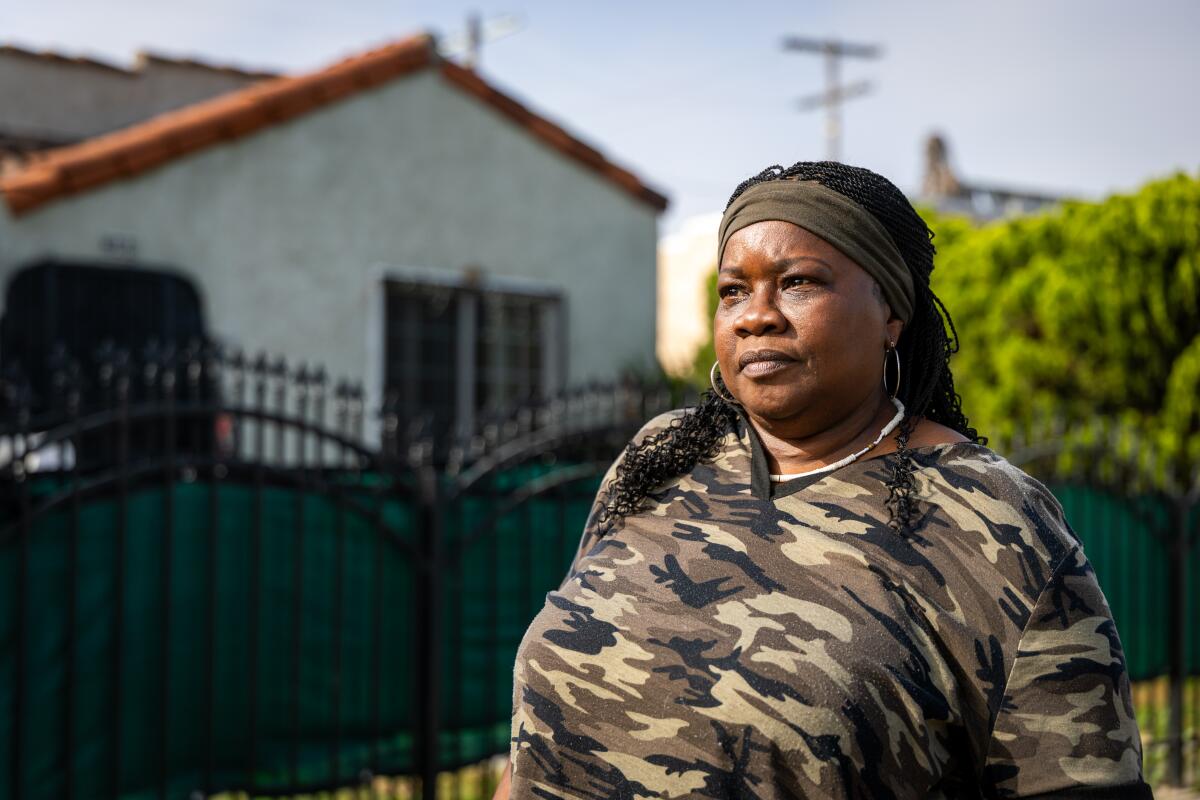 A woman stands outside a home.
