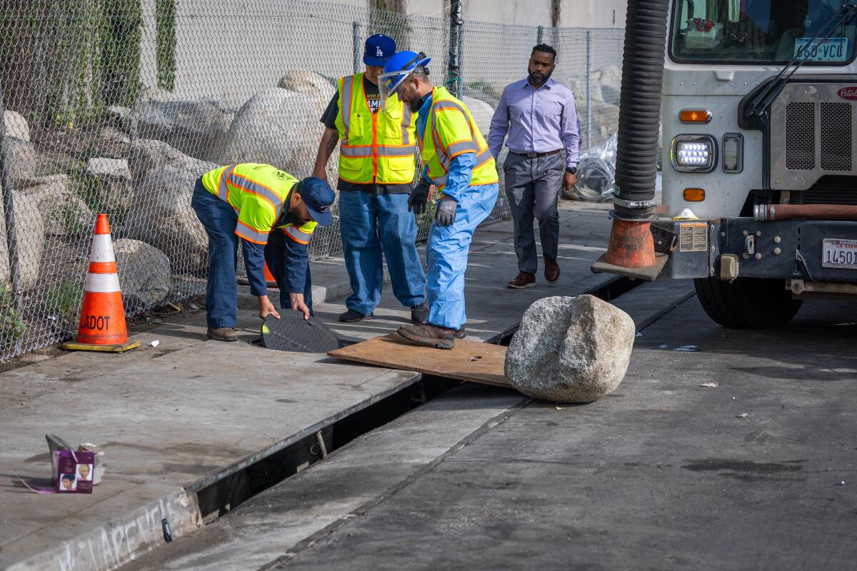 Workers prepare to cover a storm drain.