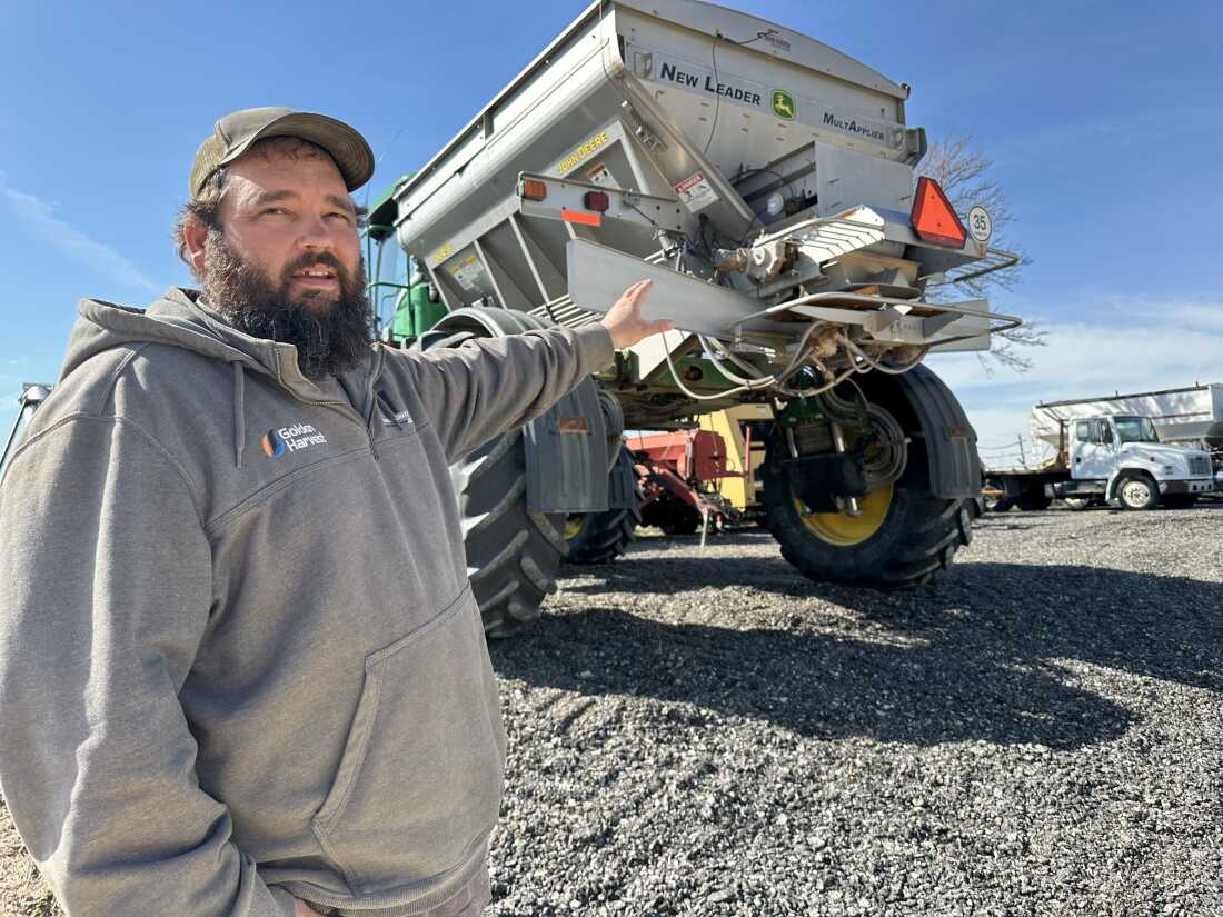 Matt Ubel, standing on his farm near Wheaton, Kansas, motions to the fertilizer spreader he’ll use to spread urea fertilizer this spring.