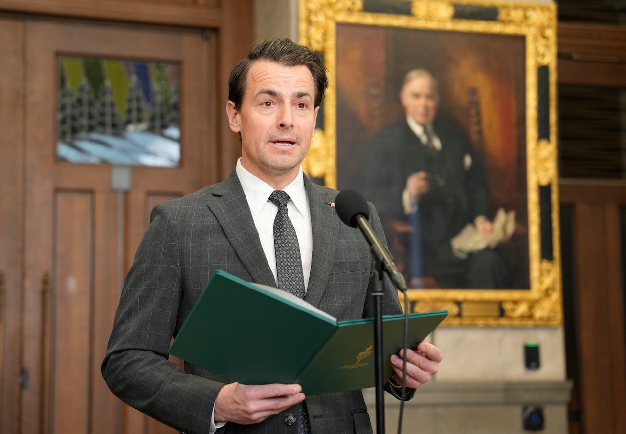 A man speaks at a podium while holding a book.