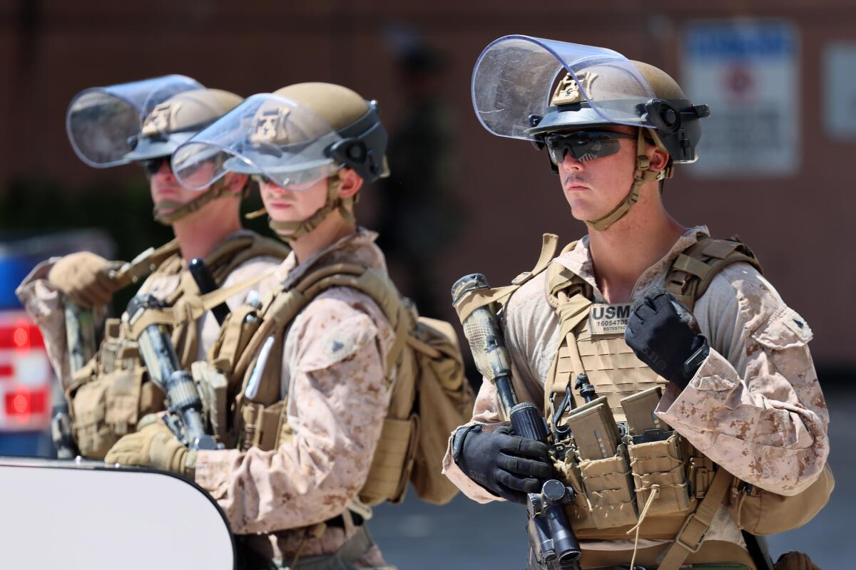 Three Marines stand together wearing protective gear.