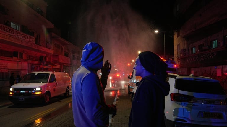 Residents look on as first responders work at the site...