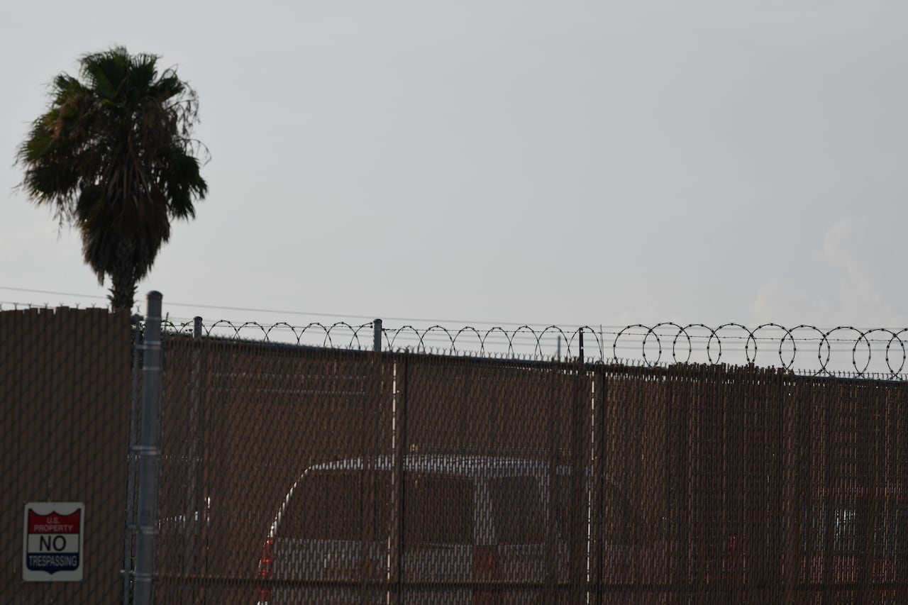 A detention facility behind a chain-link fence.