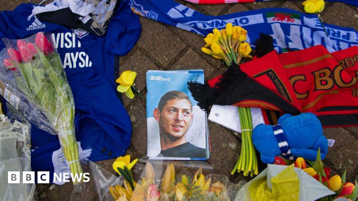 Flowers and football tops and scarves on the ground, surrounding a photograph of a young man, on the front of a magazine entitled "Bluebird".