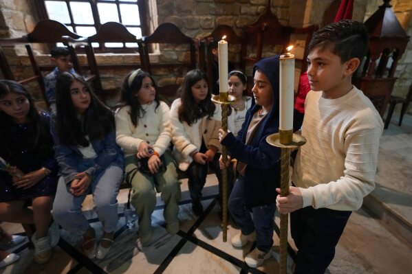 Boys hold candles during Palm Sunday Mass procession at Saint Thomas Cathedral, in the southern port city of Tyre, south Lebanon, Sunday, March 29, 2026. (AP Photo/Hussein Malla)