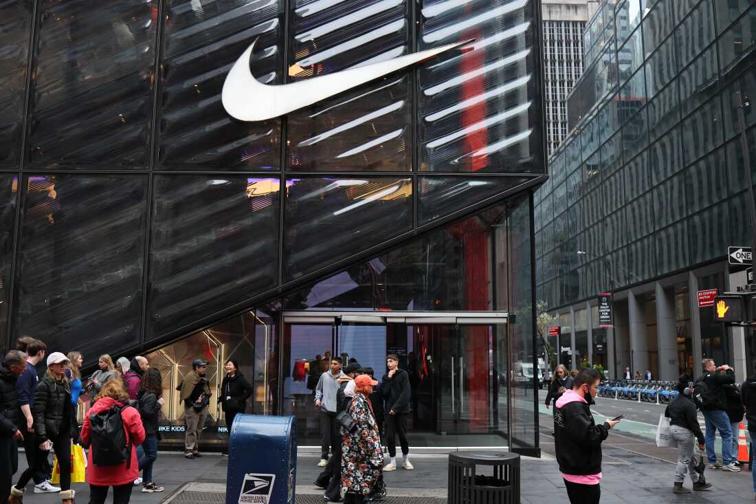 Several people walk by a Nike store with a glass facade on Fifth Avenue in New York City on April 3, 2025.
