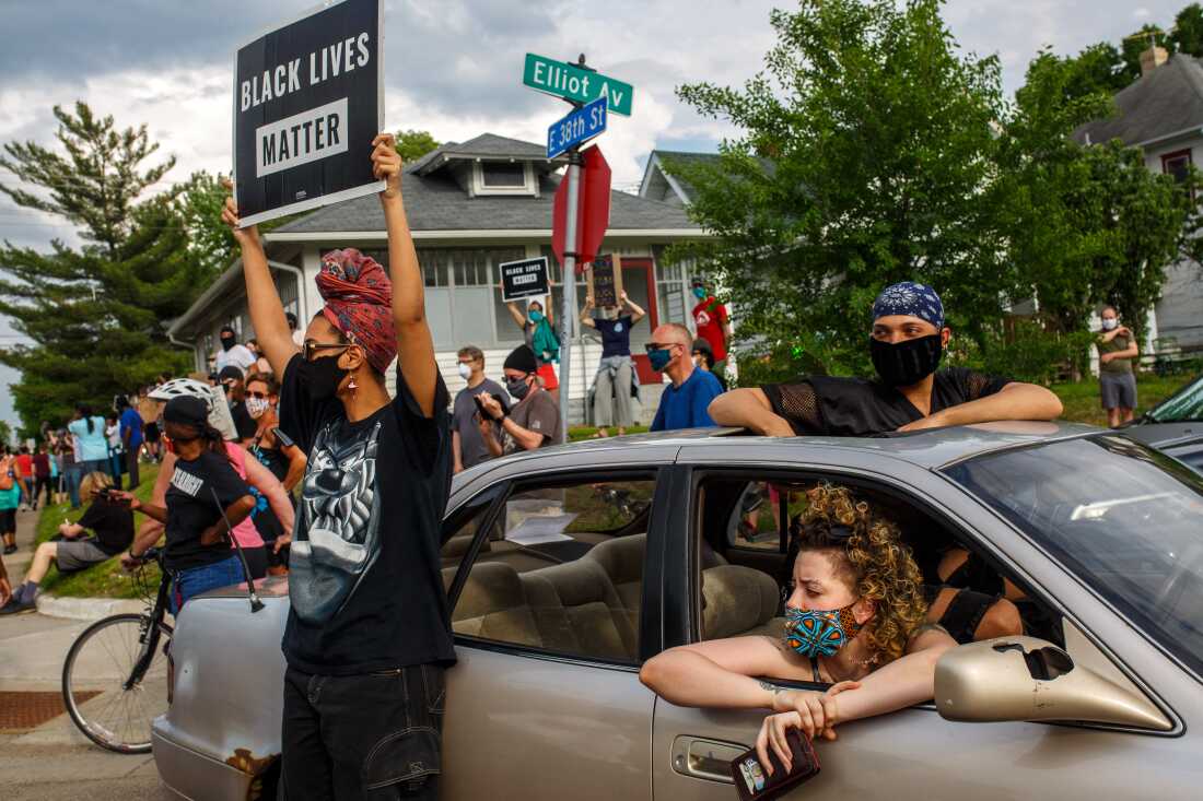 People hold signs and protest after a Minneapolis police officer murdered George Floyd in May 2020.
