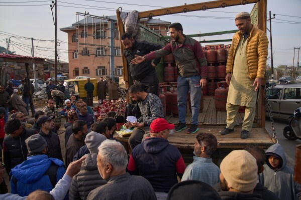 People wait to collect household cylinders of liquefied natural gas from an authorized dealer on a roadside in Srinagar, Indian-controlled Kashmir, Saturday, March 14, 2026. (AP Photo/Dar Yasin)