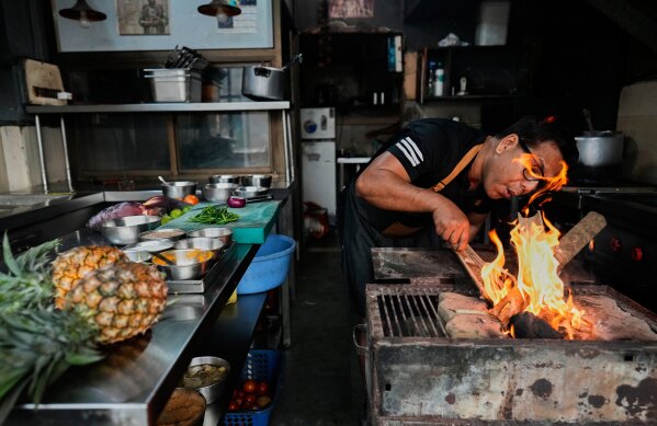 Atul Lahkar, from the Assam region, chef lights a fire with wood and coal to prepare food for his restaurant following a regional gas shortage in Guwahati, India, Thursday, March 19, 2026. (AP Photo/Anupam Nath)