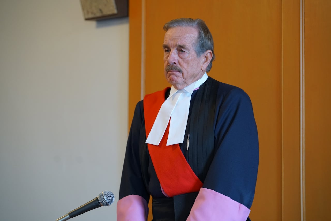 A judge standing at the front of the courtroom.