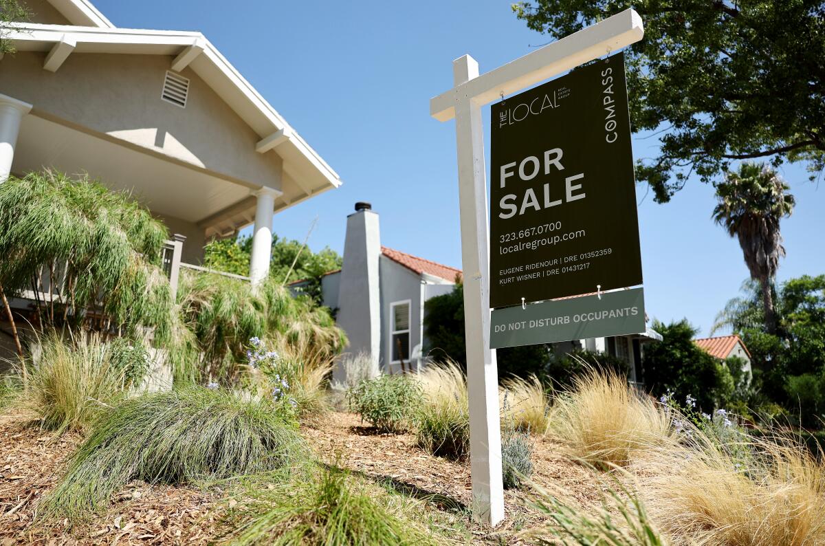 A "For Sale" sign in front of a house.