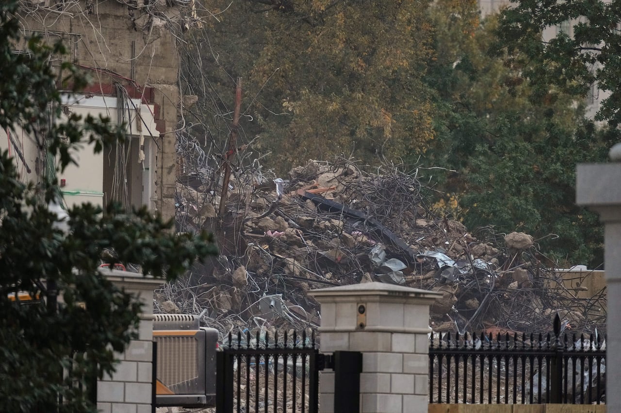 A pile of metal and boulders behind a black wrought iron fence