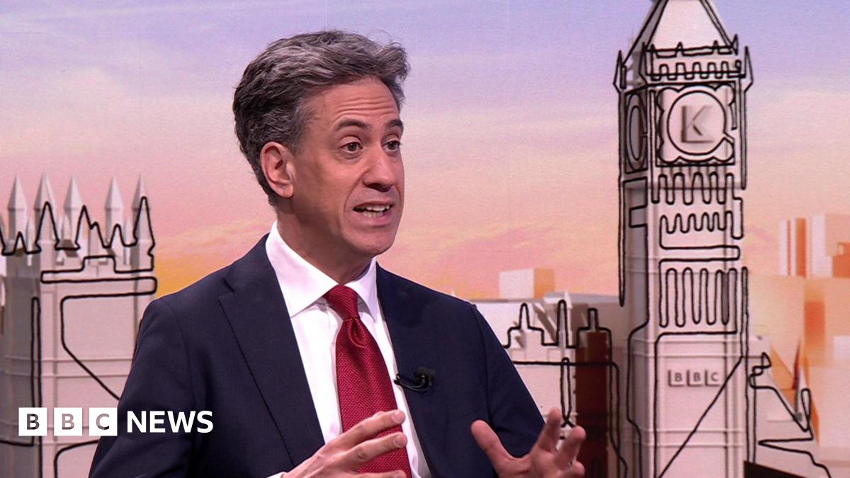 Energy Secretary Ed Miliband speaking on the Sunday with Laura Kuenssberg programme. He wears a dark navy suit, a white shirt and a ruby red satin tie.