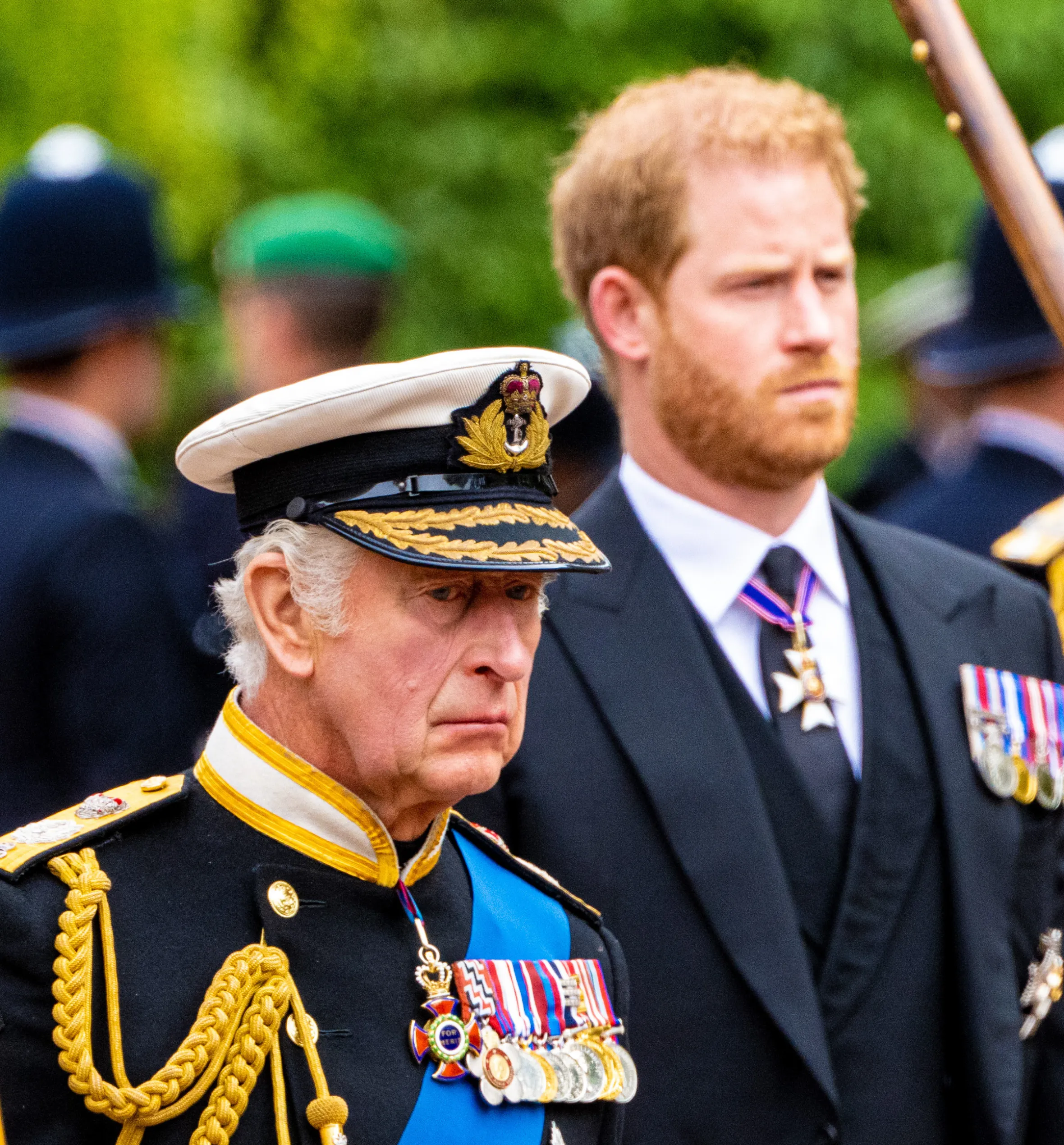 King Charles III in military uniform and Prince Harry in a suit.