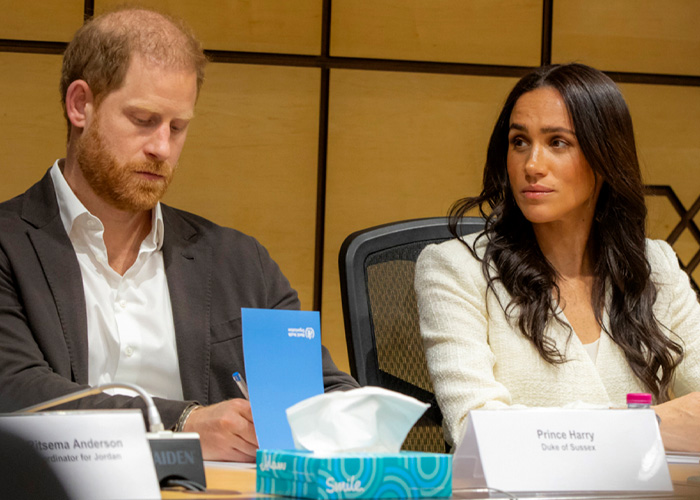 Prince Harry and Meghan Markle seated at a meeting table, appearing focused amid emerging bombshell claims.