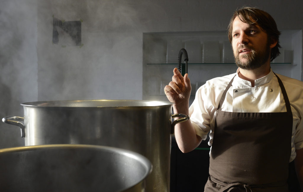 Redzepi, chef and co-owner of the restaurant Noma, talks with his employees in a test kitchen in his restaurant in Copenhagen