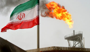 A gas flare on an oil production platform is seen alongside an Iranian flag in the Gulf